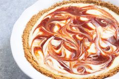 a pie with chocolate swirl on top in a white bowl next to a fork and knife