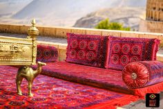 a red and gold couch sitting on top of a rug next to a golden statue