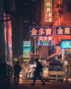 a busy city street at night with neon signs on the buildings and people walking by