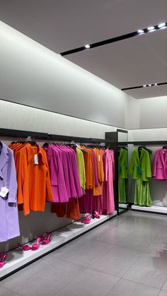 there are many different colored clothes on display