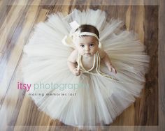 a baby girl wearing a white tutu and pearls