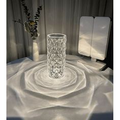 a glass vase sitting on top of a table next to two white vases with flowers in them