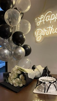 a birthday cake and balloons are on a table in front of a sign that says happy birthday