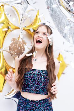 a young woman holding a clock and confetti sticks in front of her face