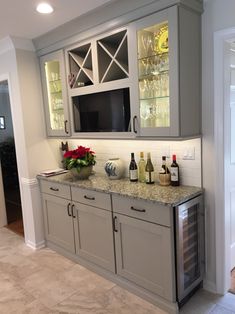 a kitchen with gray cabinets and marble counter tops, wine glasses on the cabinet doors