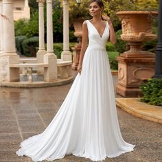 a woman in a white wedding dress posing for the camera with her hand on her hip