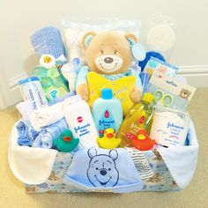 a teddy bear sitting in a basket filled with baby items