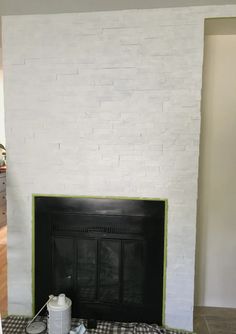 the fireplace is being painted white and has black trim on it's brick surround