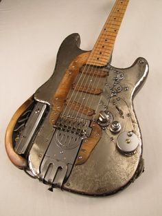 an old guitar that is sitting on a white tablecloth with a metal band around it's neck