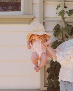 a woman holding a baby up to her face while standing next to a white house