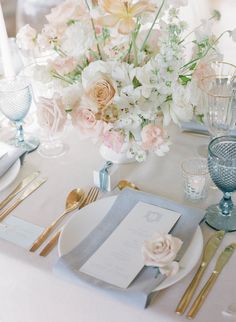 the table is set with silverware and flowers