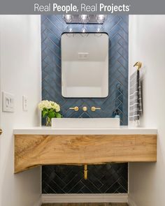 a bathroom with blue tile and wooden counter top, gold faucet, and white sink