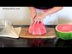 a person cutting up a piece of watermelon on top of a wooden cutting board