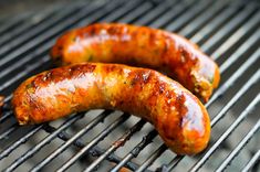 two sausages are cooking on the grill