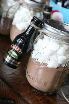 two mason jars filled with marshmallows sitting on a wooden table next to a beer bottle