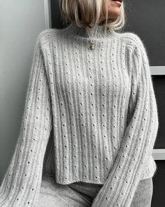 a woman wearing a gray sweater and grey pants