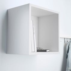 a white book shelf with books and a remote control on the wall next to it