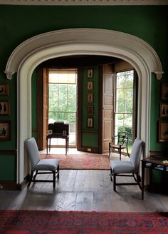 an arched doorway leads into a green room with two chairs and a rug on the floor