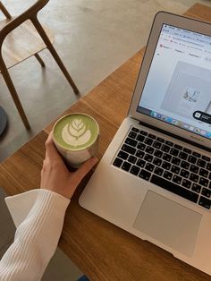 a person sitting at a table with a cup of coffee in front of their laptop