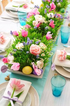 the table is set with plates and flowers in vases, napkins and place settings