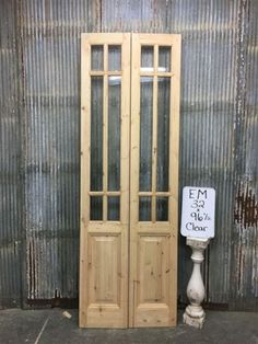 two wooden doors sitting side by side in front of a metal wall with a sign on it