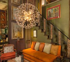 a living room filled with furniture and a chandelier hanging from the ceiling above it