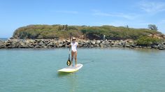 a person standing on a surfboard in the water with an island in the background