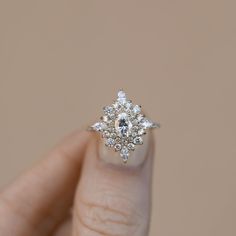 a woman's hand holding an engagement ring with diamonds on the top and bottom