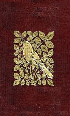 a bird sitting on top of a red book with gold trimmings and leaves