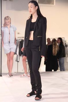 a woman standing in front of a mirror wearing black pants and a cropped top