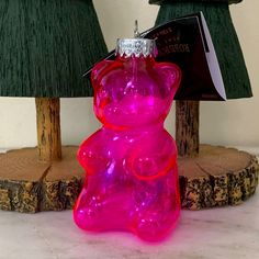 a pink glass bear ornament sitting on top of a table next to two green lamps