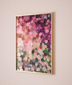 a painting hanging on the wall next to a vase with flowers in it and a potted plant