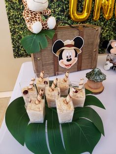 a table topped with desserts next to a jungle themed sign and animal figurines