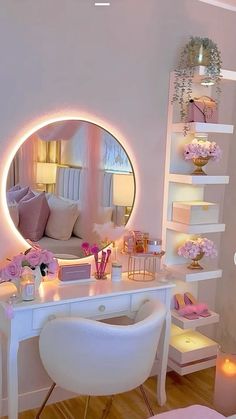 a white desk topped with a mirror next to a chair and a table covered in pink flowers