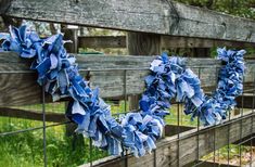 two blue wreaths are hanging on a fence