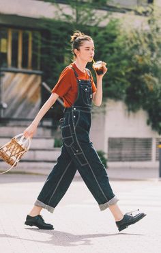 a woman walking down the street while holding a basket and an apple in her hand