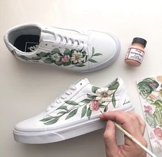 someone is painting flowers on their white shoes