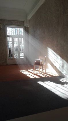 the sun is shining in an empty room with a chair and table on the floor