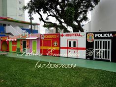 a row of brightly colored play houses on the side of a road with trees in the background