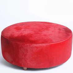 a red round ottoman sitting on top of a white floor next to a wooden base