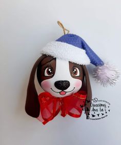 a brown and white dog wearing a santa hat with a red bow on it's head