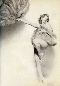 an old fashion photo of a woman holding a large feathered object in her hand