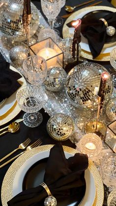 a black and gold table setting with disco ball centerpieces, silverware, and napkins