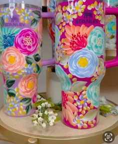 two colorful coffee mugs with flowers painted on them