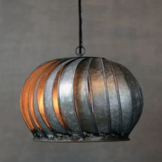 a metal light hanging from a ceiling fixture with wood strips on the top and bottom