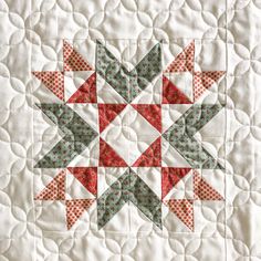 a quilted table topper with red, green and white stars in the center