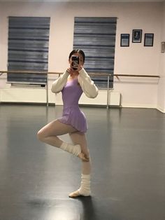 a ballerina taking a selfie with her cell phone in an empty dance studio