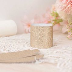 a close up of a cup on a doily with flowers in the back ground