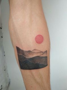 a man's leg with a mountain landscape tattoo on his left calf, and a red dot in the middle