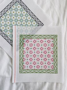 three cross - stitch patterns are displayed on top of each other, one in green and the other in pink